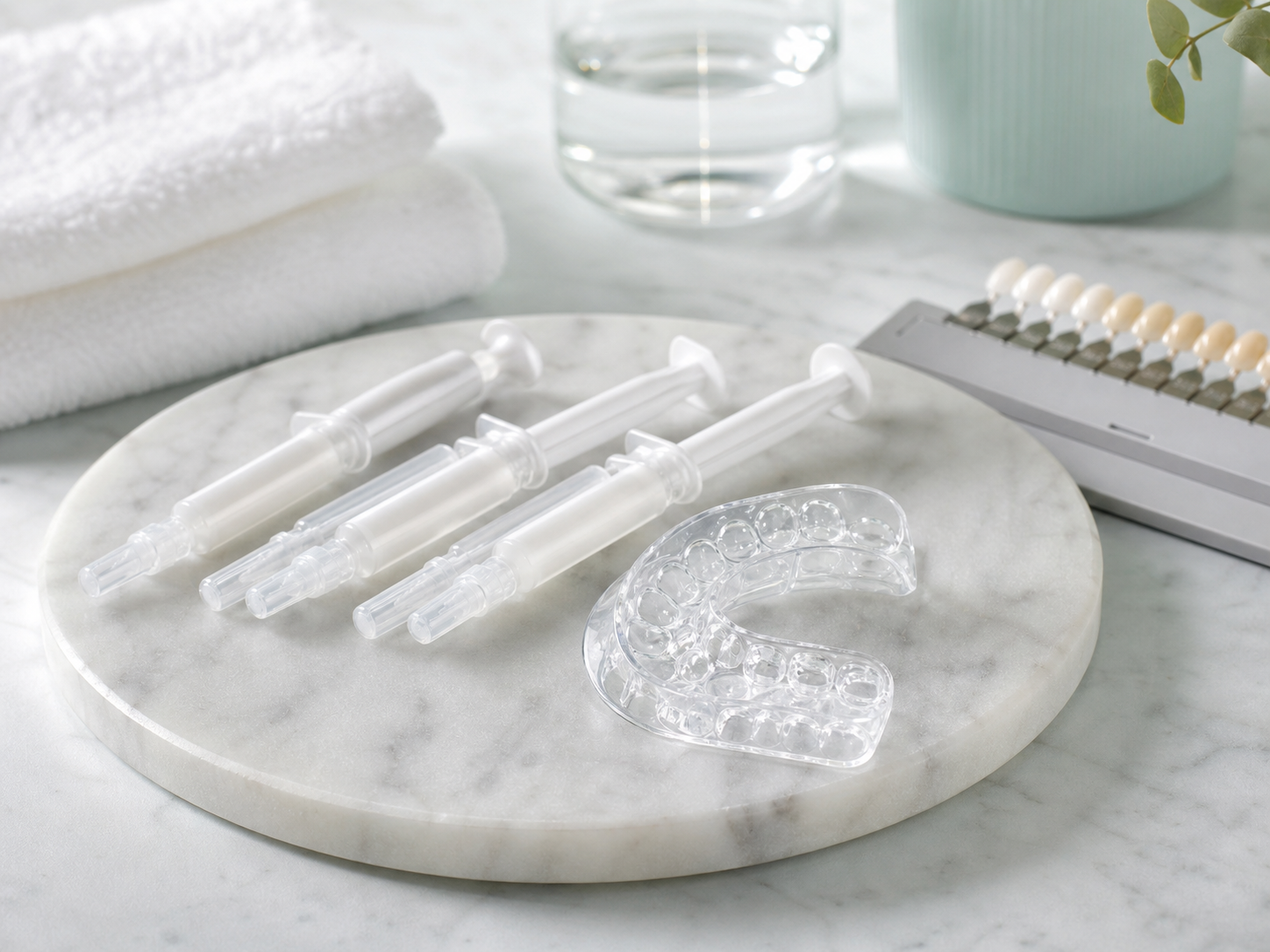 Unmarkierte Whitening-Gel-Spritzen, Zahnschiene und Farbskala auf einer sauberen Oberfläche